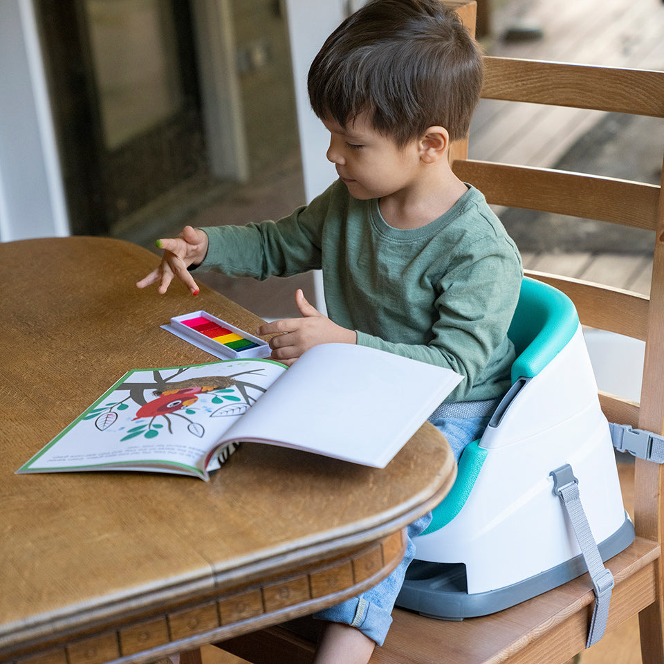 boy in a baby chair reading at the table