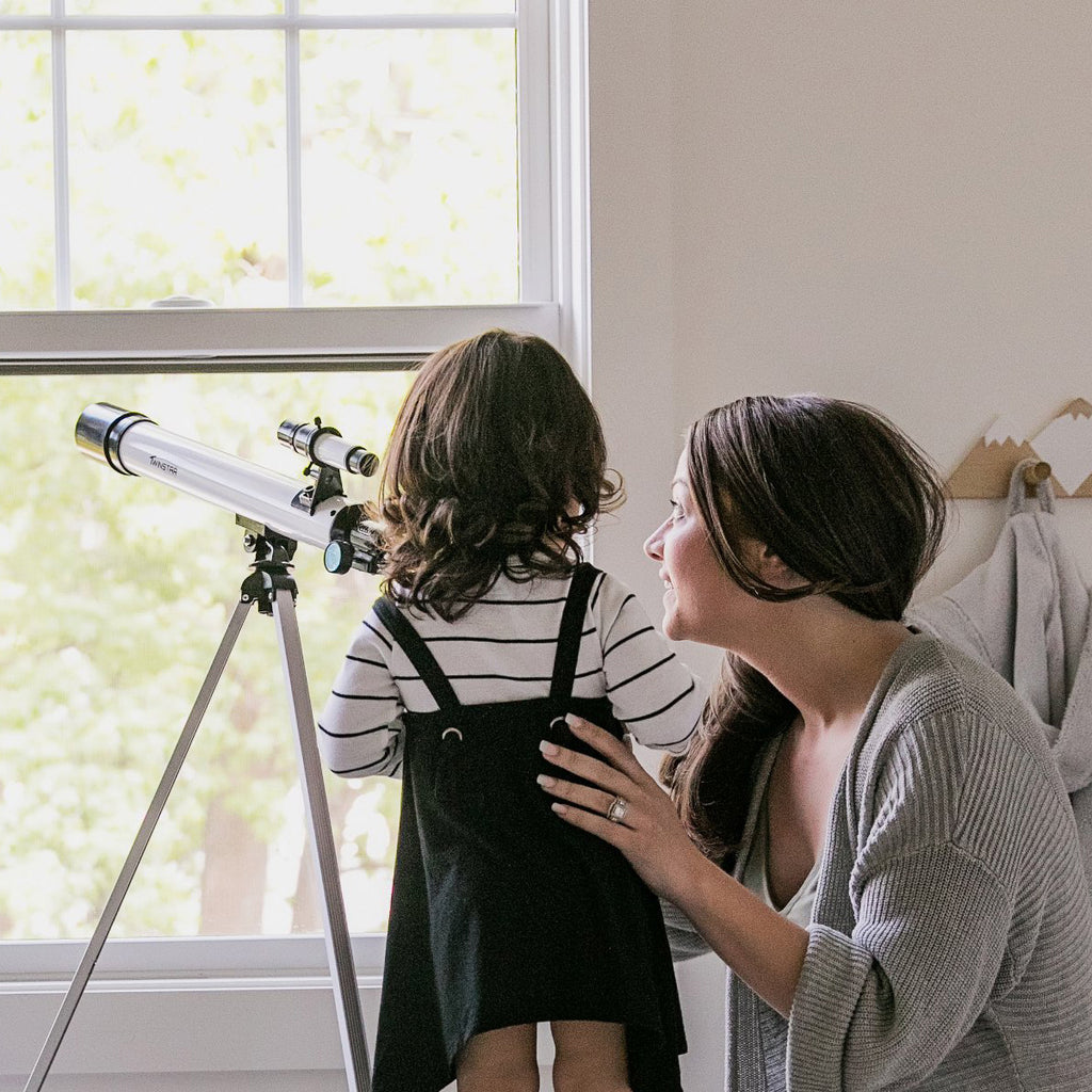 young girl with mom looking through a telescope